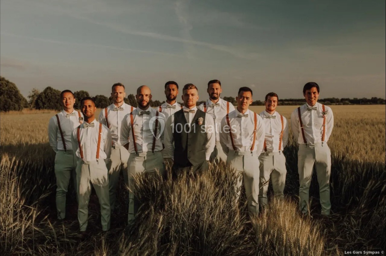 Un groupe d'hommes en tenue formelle, debout dans un champ au coucher du soleil.