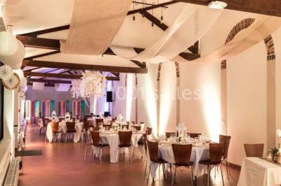 Salle de réunion avec une grande table rectangulaire, chaises noires, documents, bouteilles d'eau et écran de présentation.