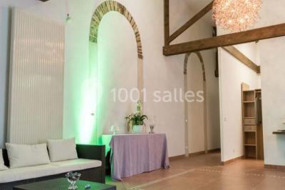 Salle de réunion avec une grande table rectangulaire, chaises noires, documents, bouteilles d'eau et écran de présentation.