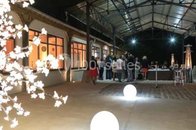 Salle de réunion avec une grande table rectangulaire, chaises noires, documents, bouteilles d'eau et écran de présentation.
