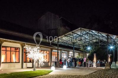 Salle de réunion avec une grande table rectangulaire, chaises noires, documents, bouteilles d'eau et écran de présentation.