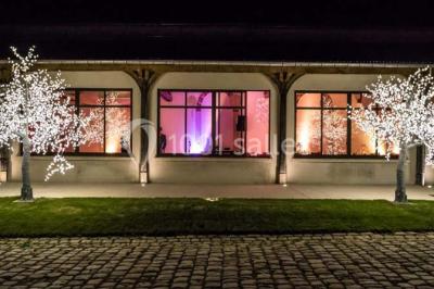 Salle de réunion avec une grande table rectangulaire, chaises noires, documents, bouteilles d'eau et écran de présentation.