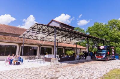 Salle de réunion avec une grande table rectangulaire, chaises noires, documents, bouteilles d'eau et écran de présentation.