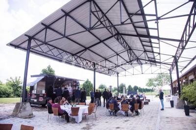 Salle de réunion avec une grande table rectangulaire, chaises noires, documents, bouteilles d'eau et écran de présentation.