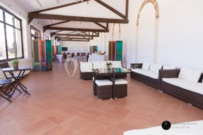 Salle de réunion avec une grande table rectangulaire, chaises noires, documents, bouteilles d'eau et écran de présentation.