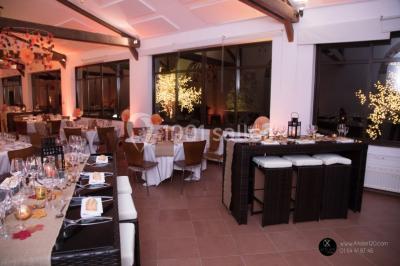 Salle de réunion avec une grande table rectangulaire, chaises noires, documents, bouteilles d'eau et écran de présentation.