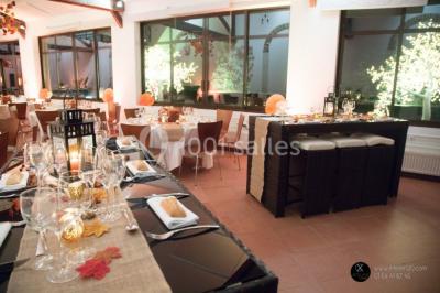 Salle de réunion avec une grande table rectangulaire, chaises noires, documents, bouteilles d'eau et écran de présentation.