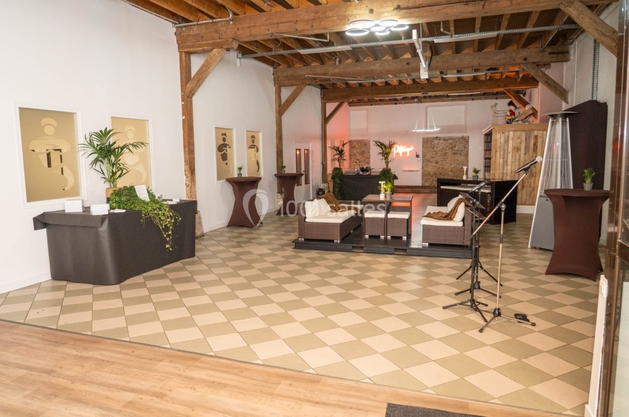 Salle lumineuse avec sol en carrelage, mobilier en rotin, plantes décoratives et plafond en bois apparent.