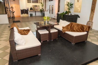 Salle de réunion avec une grande table rectangulaire, chaises noires, documents, bouteilles d'eau et écran de présentation.