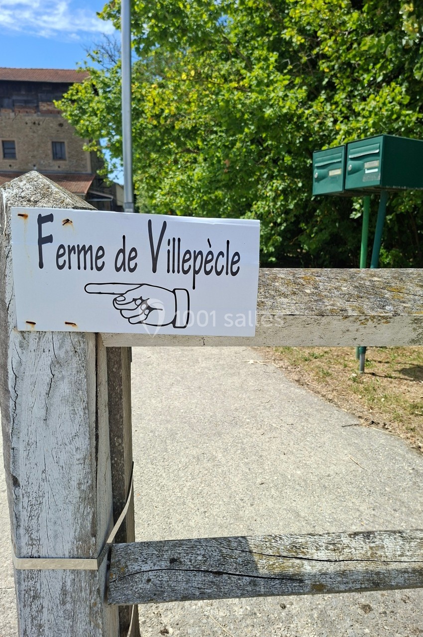 Panneau ’Ferme de Villepècle’ fixé sur une barrière en bois, avec une flèche pointant vers la gauche.