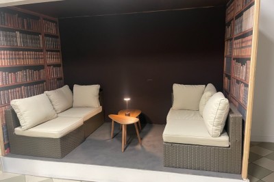 Salle de réunion avec une grande table rectangulaire, chaises noires, documents, bouteilles d'eau et écran de présentation.