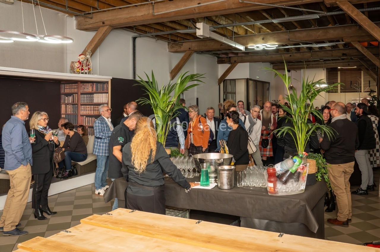 Groupe de personnes discutant dans une salle avec des plantes, un buffet et une ambiance conviviale.
