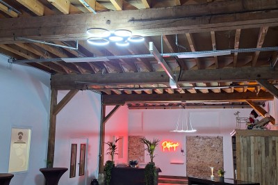 Salle de réunion avec une grande table rectangulaire, chaises noires, documents, bouteilles d'eau et écran de présentation.