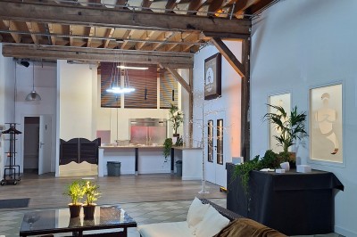 Salle de réunion avec une grande table rectangulaire, chaises noires, documents, bouteilles d'eau et écran de présentation.