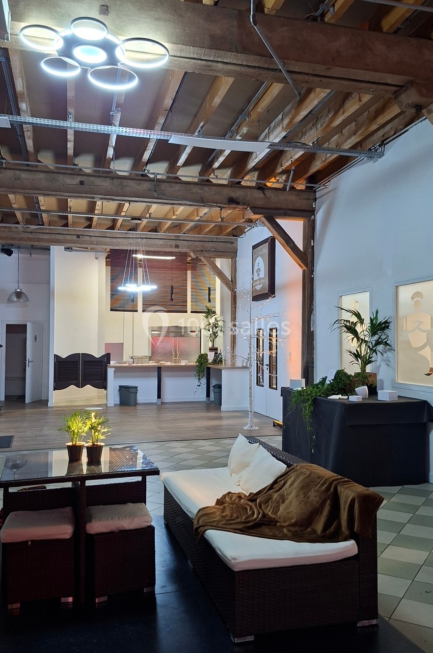 Espace intérieur avec plafond en bois, canapé, table basse, plantes et éclairage moderne dans un cadre lumineux.