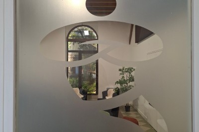 Salle de réunion avec une grande table rectangulaire, chaises noires, documents, bouteilles d'eau et écran de présentation.