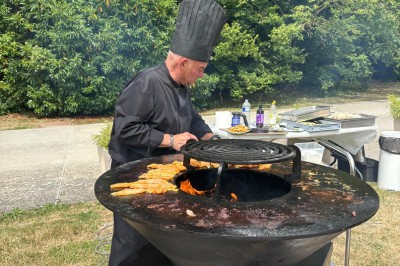 Salle de réunion avec une grande table rectangulaire, chaises noires, documents, bouteilles d'eau et écran de présentation.