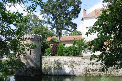 Salle de réunion avec une grande table rectangulaire, chaises noires, documents, bouteilles d'eau et écran de présentation.