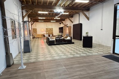 Salle de réunion avec une grande table rectangulaire, chaises noires, documents, bouteilles d'eau et écran de présentation.