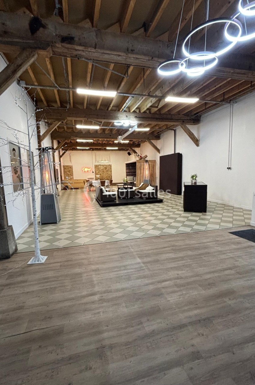 Espace intérieur spacieux avec plafond en bois, sol carrelé et parquet, mobilier moderne et éclairage design.