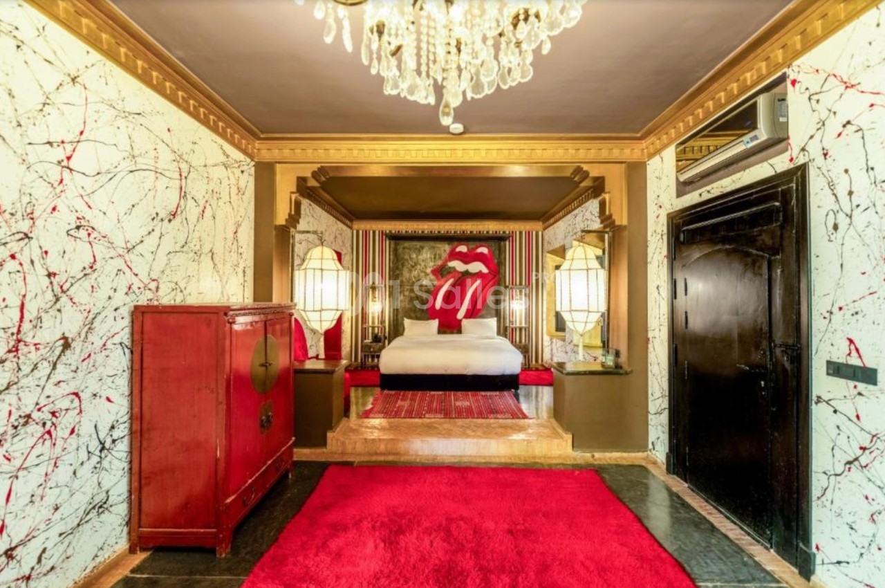 Chambre décorée avec un lit orné d'un motif de lèvres rouges, murs texturés et lustre en cristal.