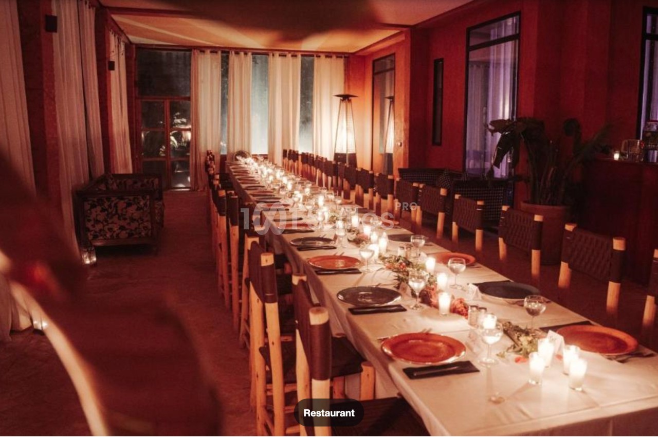 Grande table dressée pour un dîner, ornée de bougies et de décorations, dans une salle chaleureusement éclairée.