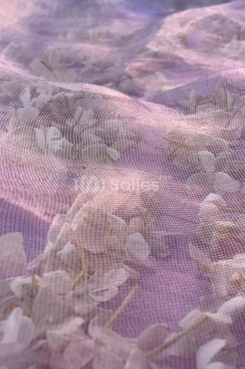 Fleurs blanches floues sous un tissu translucide rose éclairé par une lumière douce.