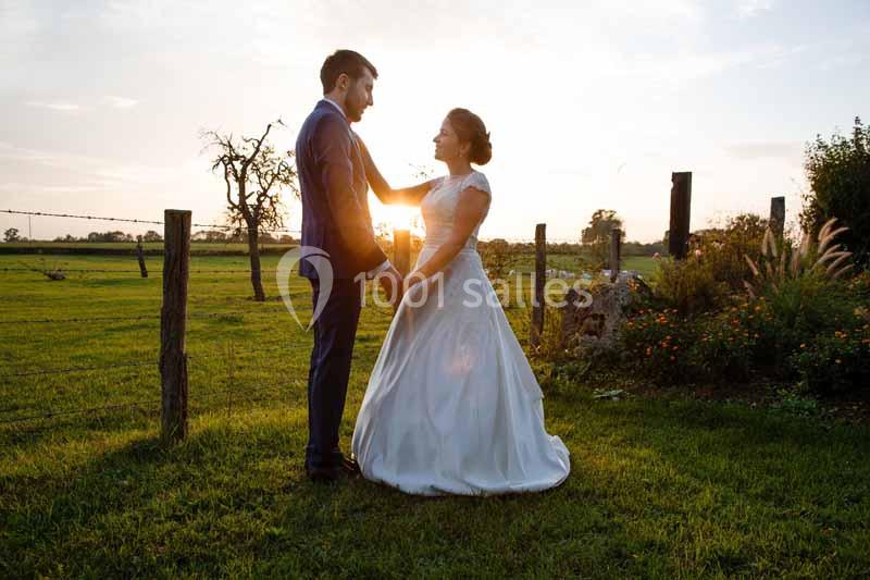 Location salle Maligny (Côte-d'Or) - Domaine du Grand Nanteux #10 Un couple en tenue de mariage se tient debout dans un champ au coucher du soleil.