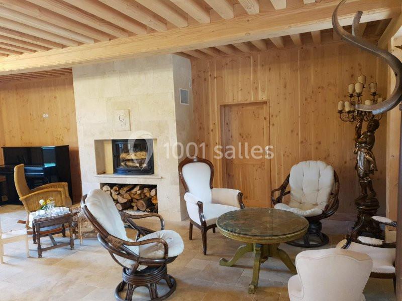 Location salle Maligny (Côte-d'Or) - Domaine du Grand Nanteux #22 Salon chaleureux avec murs en bois, cheminée moderne, fauteuils en osier et en tissu, table ronde et décoration rustique.