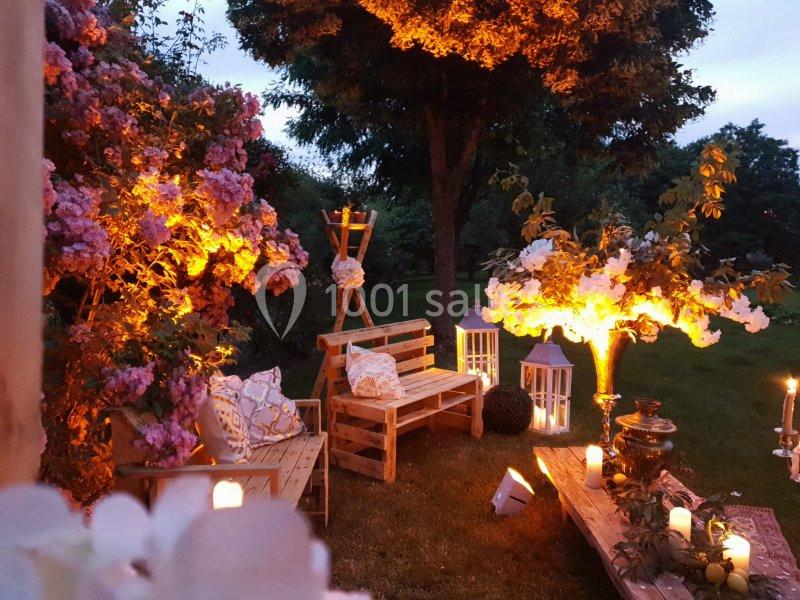 Location salle Maligny (Côte-d'Or) - Domaine du Grand Nanteux #23 Espace extérieur aménagé avec des bancs en bois, lanternes et bougies, entouré de fleurs et éclairé à la tombée de la nuit.