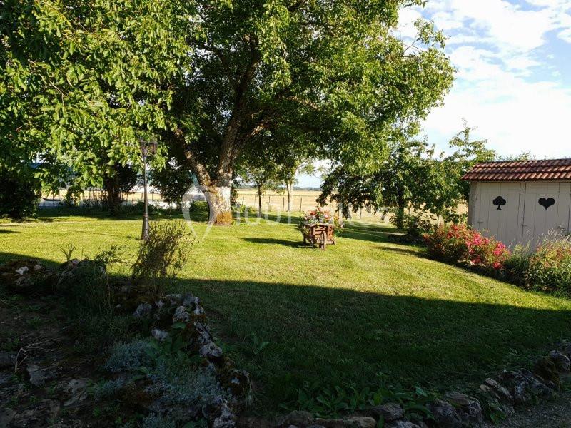 Location salle Maligny (Côte-d'Or) - Domaine du Grand Nanteux #17 Jardin verdoyant avec arbres, pelouse, table en bois au centre et cabanon blanc décoré de cœurs en arrière-plan.