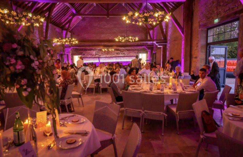 Location salle Maligny (Côte-d'Or) - Domaine du Grand Nanteux #26 Salle de réception décorée avec des tables dressées, des invités assis et un éclairage violet chaleureux.