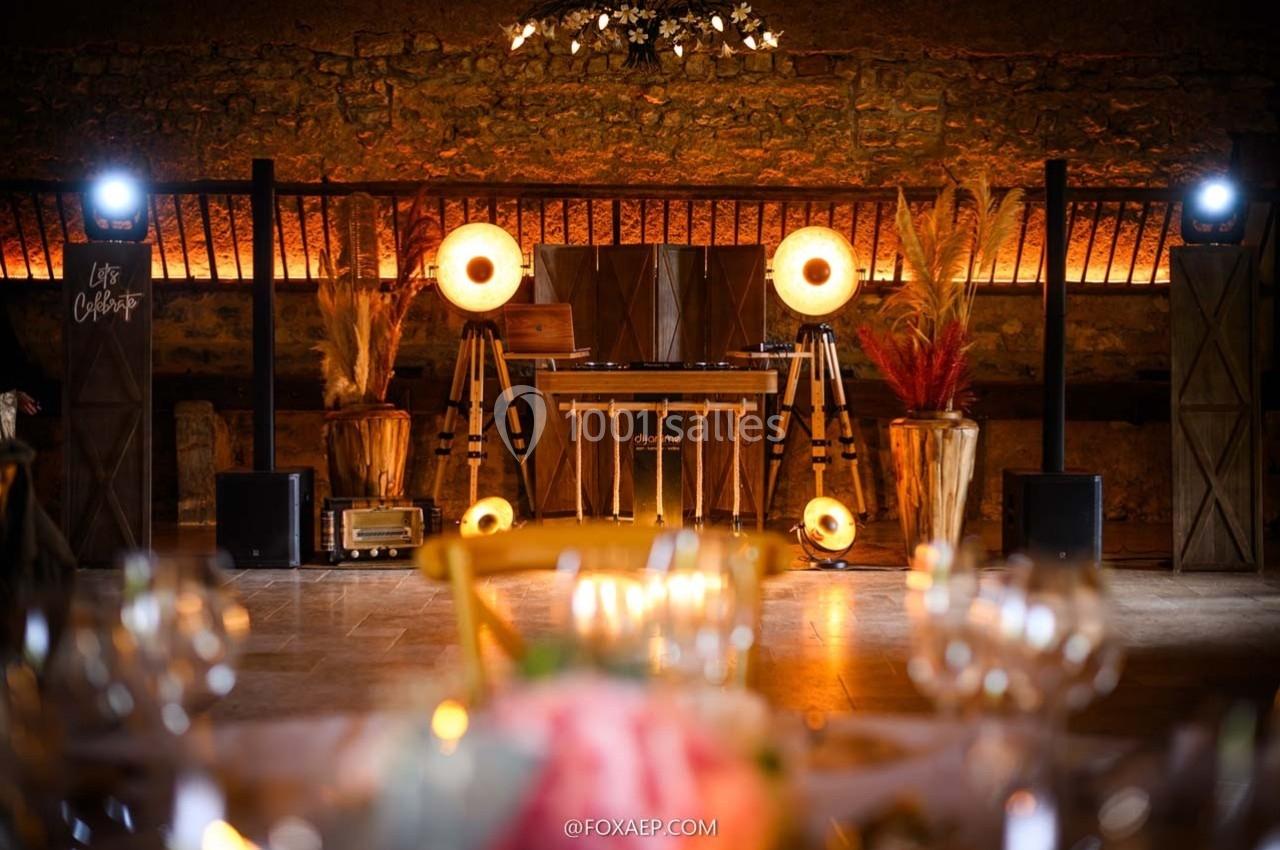 Location salle Maligny (Côte-d'Or) - Domaine du Grand Nanteux #28 Installation de DJ avec éclairage chaleureux, décor rustique et plantes séchées dans une salle en pierre.