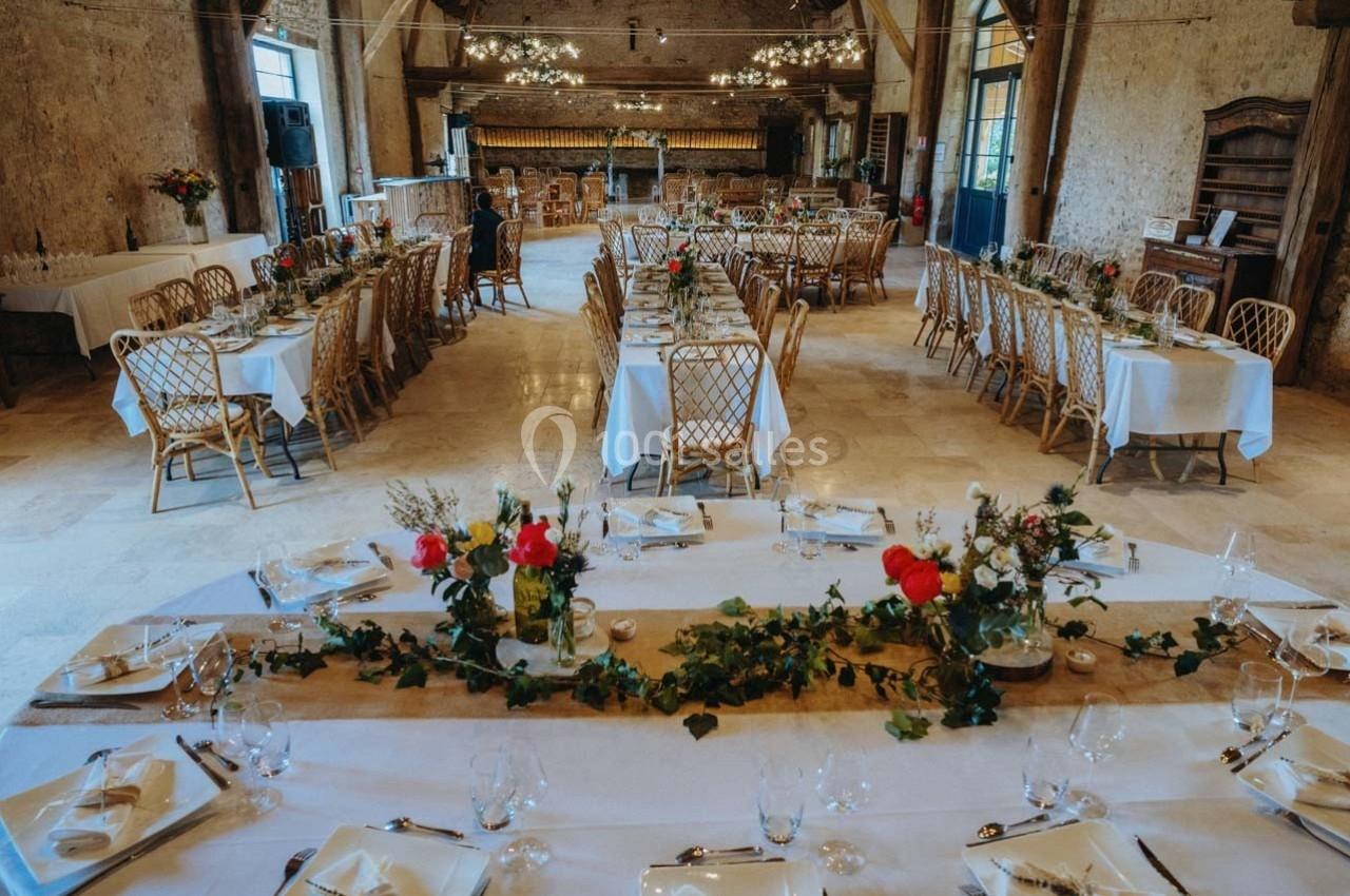 Location salle Maligny (Côte-d'Or) - Domaine du Grand Nanteux #6 Salle de réception décorée avec des tables dressées, nappes blanches, chaises en rotin et guirlandes végétales.