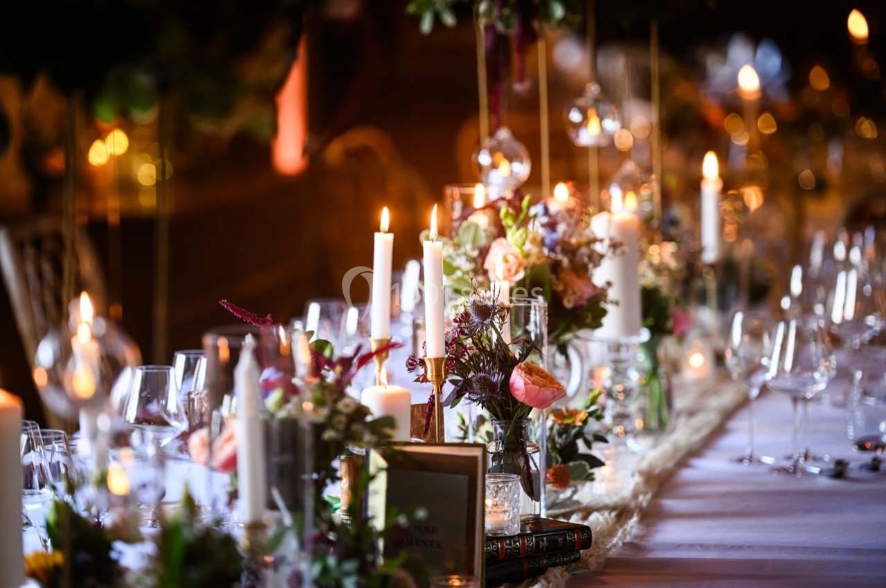 Location salle Maligny (Côte-d'Or) - Domaine du Grand Nanteux #34 Table élégamment décorée avec bougies allumées, fleurs colorées et verres disposés pour un dîner festif.