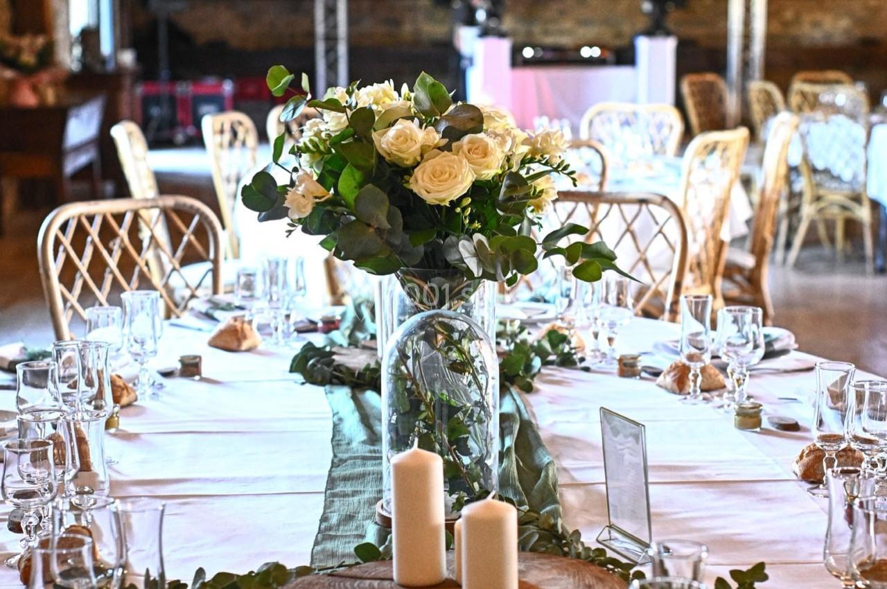 Location salle Maligny (Côte-d'Or) - Domaine du Grand Nanteux #35 Table décorée pour un événement avec fleurs blanches, bougies et vaisselle élégante dans une salle rustique.