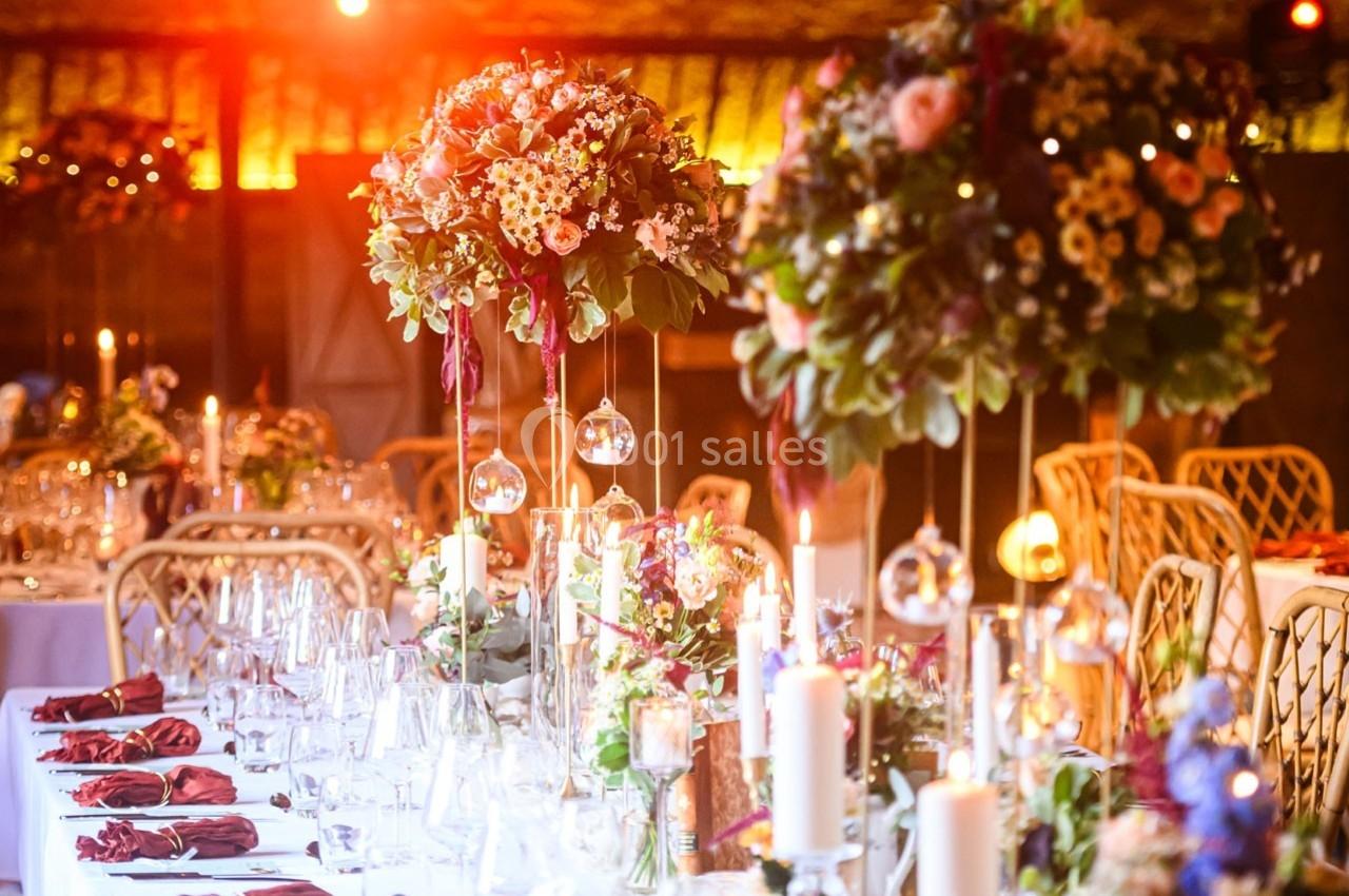 Location salle Maligny (Côte-d'Or) - Domaine du Grand Nanteux #36 Tables décorées pour un événement avec chandeliers, compositions florales suspendues et lumière tamisée.
