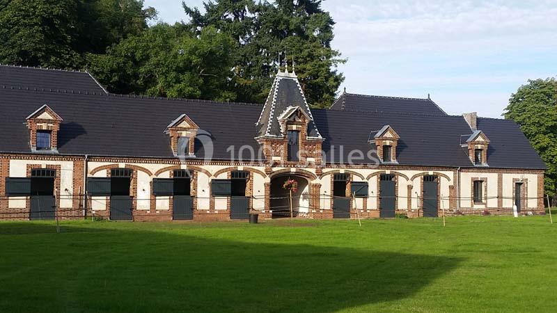 Location salle Sylvains-les-Moulins (Eure) - Domaine de Coulonge #9 Bâtiment en briques avec toit en ardoise, entouré de pelouse, comprenant plusieurs portes et fenêtres symétriques.