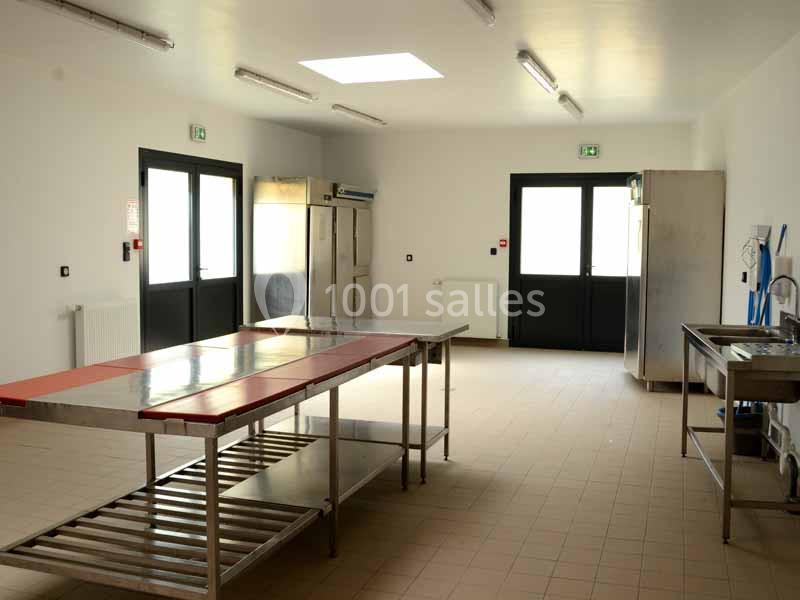Location salle Sylvains-les-Moulins (Eure) - Domaine de Coulonge #26 Cuisine professionnelle vide avec plans de travail en inox, équipements de rangement et éclairage naturel par une fenêtre de…