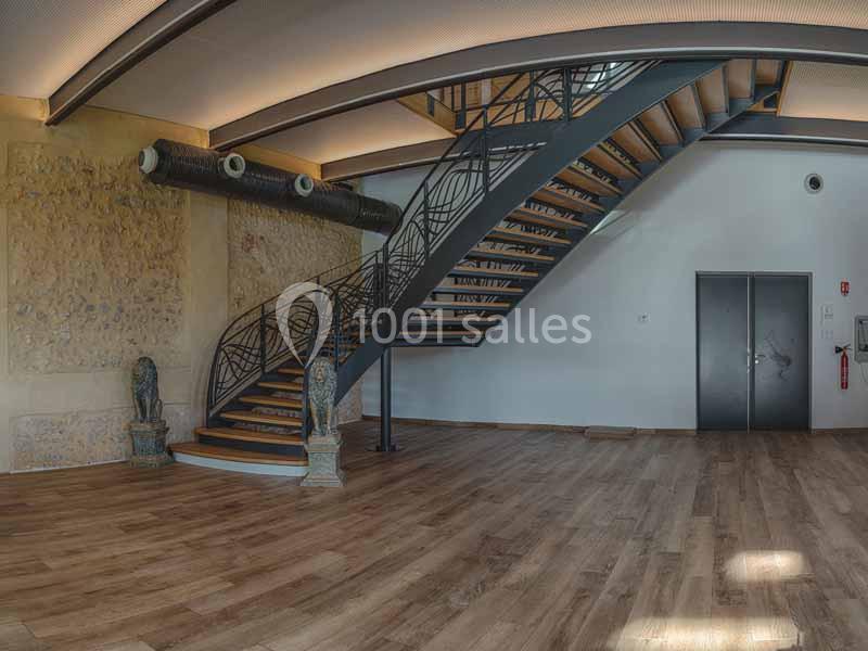 Location salle Sylvains-les-Moulins (Eure) - Domaine de Coulonge #18 Escalier métallique moderne avec garde-corps décoratif dans un intérieur spacieux au sol en bois et murs en pierre.