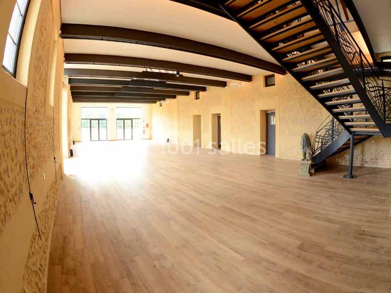 Location salle Sylvains-les-Moulins (Eure) - Domaine de Coulonge #15 Salle spacieuse avec parquet en bois, murs en pierre apparente, poutres métalliques et escalier moderne en métal.