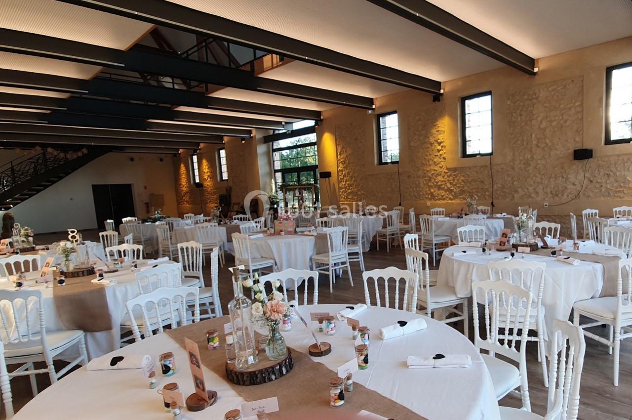 Location salle Sylvains-les-Moulins (Eure) - Domaine de Coulonge #17 Salle de réception lumineuse avec tables rondes décorées de nappes blanches, chaises assorties et centres de table floraux.