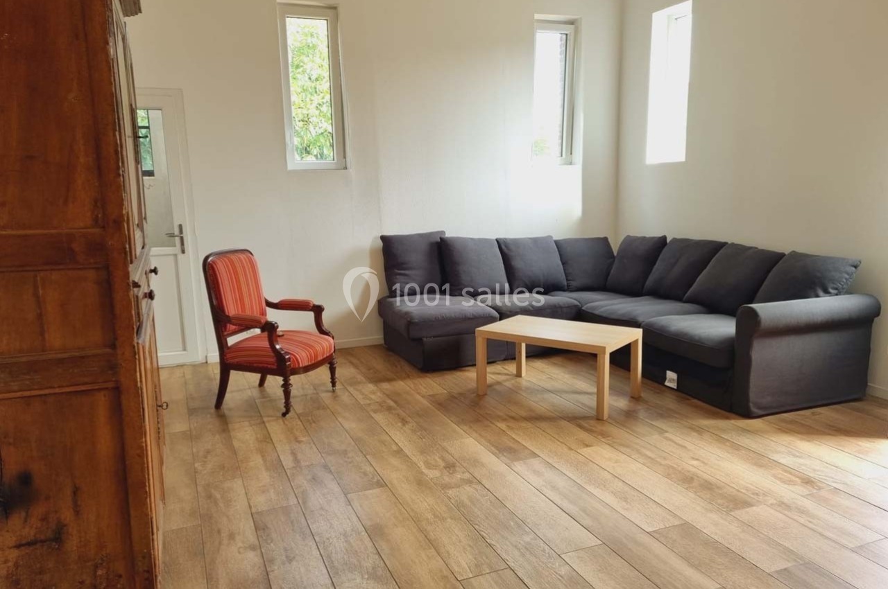 Location salle Sylvains-les-Moulins (Eure) - Domaine de Coulonge #37 Salon lumineux avec parquet, canapé d'angle gris, fauteuil rouge et table basse en bois clair.