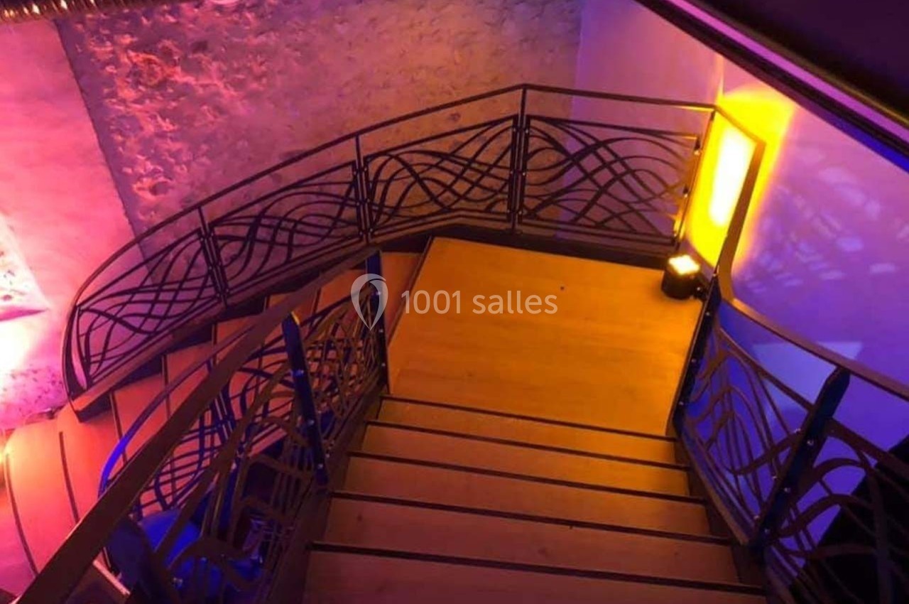 Location salle Sylvains-les-Moulins (Eure) - Domaine de Coulonge #33 Escalier en bois avec rambardes en métal décoratif, éclairé par des lumières colorées dans un intérieur moderne.