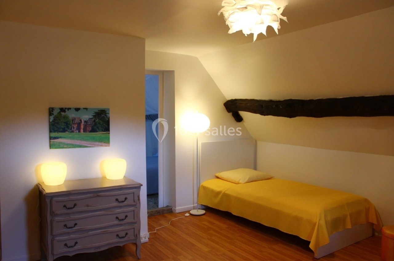 Location salle Sylvains-les-Moulins (Eure) - Domaine de Coulonge #46 Chambre mansardée avec un lit simple, une commode, deux lampes, un tableau et une poutre apparente.