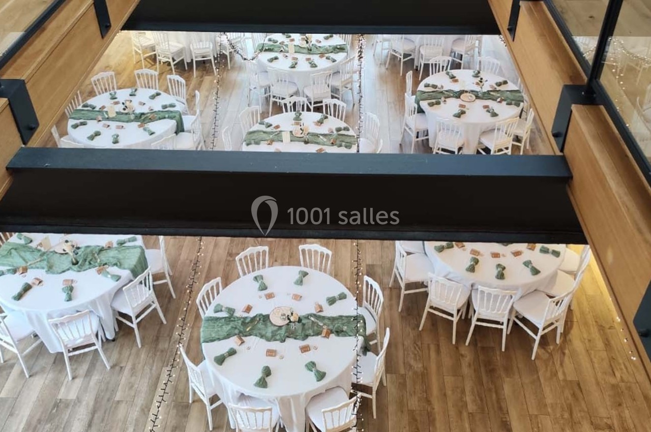 Location salle Sylvains-les-Moulins (Eure) - Domaine de Coulonge #19 Vue plongeante sur une salle de réception avec des tables rondes décorées de nappes vertes et de chaises blanches.