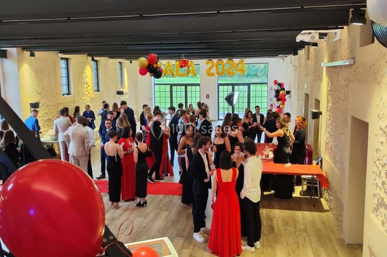 Location salle Sylvains-les-Moulins (Eure) - Domaine de Coulonge #53 Salle décorée pour un gala, avec des invités en tenue de soirée discutant autour de tables et d'un buffet.