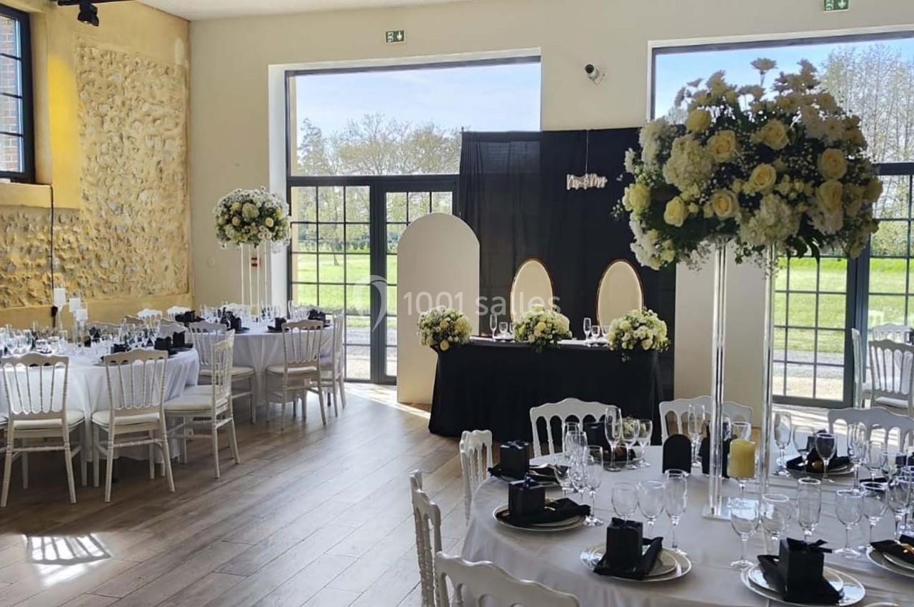Location salle Sylvains-les-Moulins (Eure) - Domaine de Coulonge #7 Salle de réception décorée avec des tables dressées, des fleurs blanches et jaunes, et de grandes baies vitrées donnant sur…