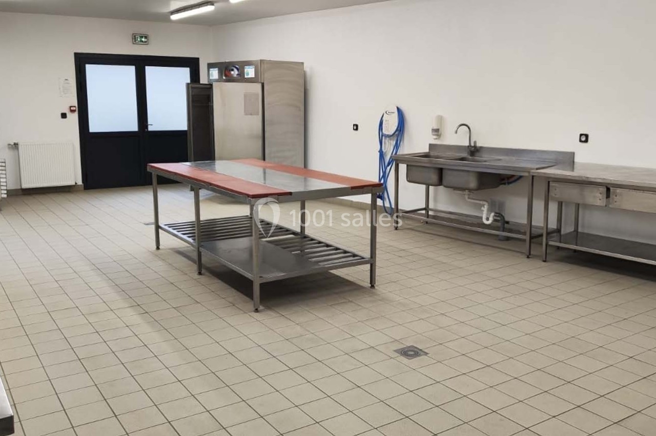 Location salle Sylvains-les-Moulins (Eure) - Domaine de Coulonge #54 Cuisine professionnelle vide avec équipements en inox, plan de travail central, évier et carrelage beige au sol.