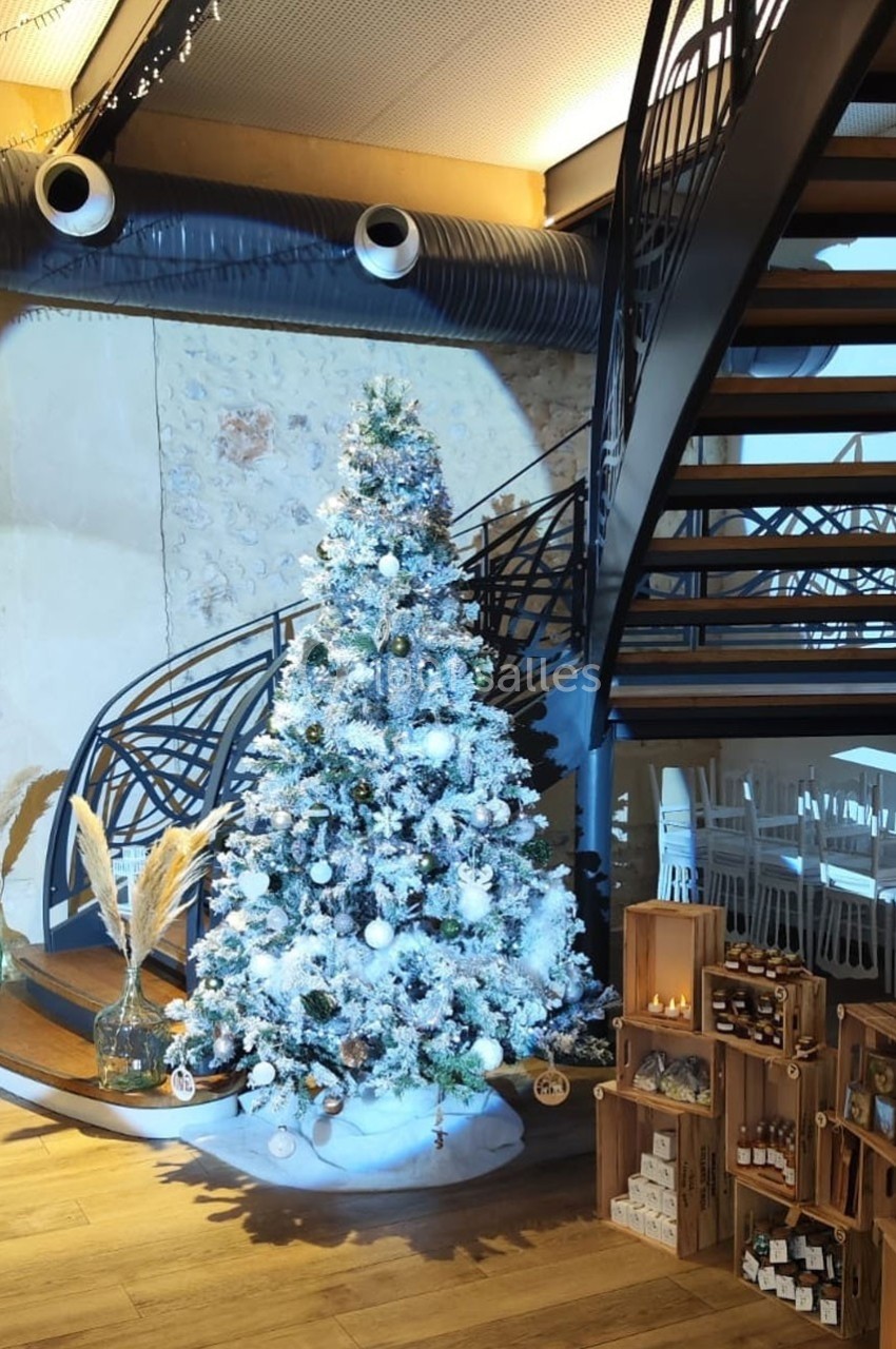 Location salle Sylvains-les-Moulins (Eure) - Domaine de Coulonge #57 Sapin de Noël décoré en blanc et argent, placé près d'un escalier métallique dans un espace intérieur lumineux.
